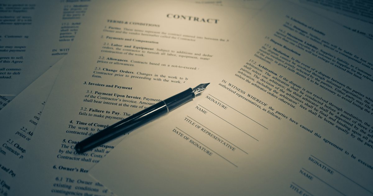 Un contrat imprimé (« Contract »), avec un stylo-plume posé dessus, entouré d'autres documents empilés.